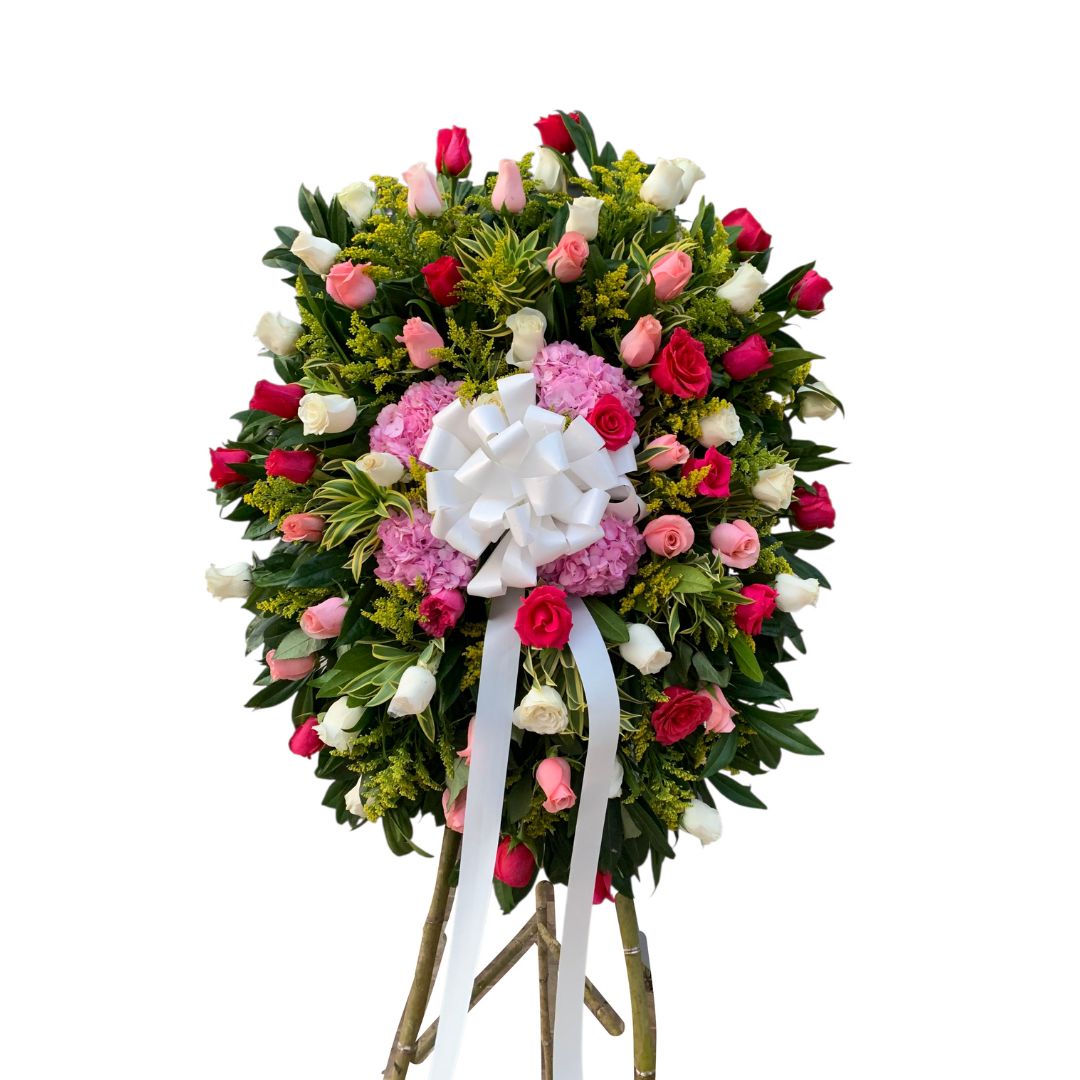 Corona fúnebre con rosas multicolor y hortensias rosadas.