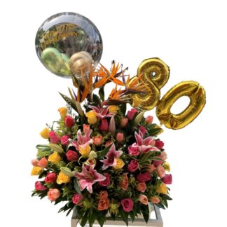 Arreglo floral de rosas de colores y lirios con globo burbuja y globos metalizados número.