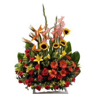 Jardinera tropical con rosas rojas y girasoles.