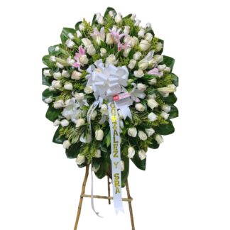 Corona fúnebre de rosas blancas y lirios.